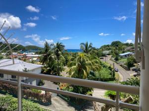 einen Balkon mit Blick auf eine Straße und Palmen in der Unterkunft Anse des Caraïbes in Les Trois-Îlets