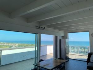 een woonkamer met een tafel en uitzicht op de oceaan bij Attico - Il Panorama in Barletta