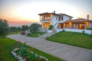 a house with a sunset in the background at Villa Almira Luxury Apartments in Ouranoupoli