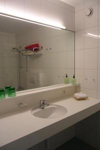 La salle de bains est pourvue d'un lavabo et d'un grand miroir. dans l'établissement Wellnesshotel Linde, à Sulzberg