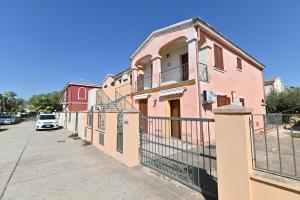 a pink building with a fence next to a street at IzzHome Lemon Tree in Pula