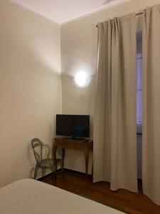 a bedroom with a bed and a desk with a television at 2SanSiro in Genoa