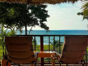duas cadeiras e uma mesa numa varanda com o oceano em Deluxe Family Suite - In front of the sea em Moñitos