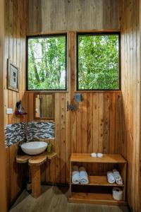 baño de madera con lavabo y 2 ventanas en Tityra Lodge, en Monteverde