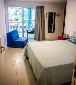a bedroom with a bed and a blue chair at apartamento vista mar in Aquiraz