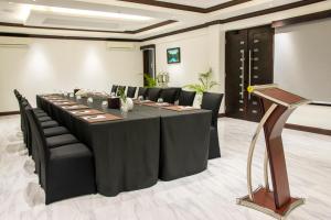 a conference room with a long table and black chairs at Sago Palm Hotel in Ocho Rios
