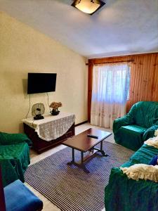 un soggiorno con 2 sedie verdi e un tavolo di Mélita Guesthouse a Braga
