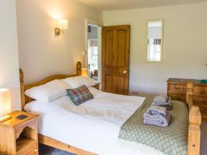 a bedroom with a white bed and a wooden cabinet at Moelwyn View Cottage in Blaenau-Ffestiniog