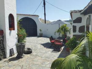a patio with a table and chairs and an umbrella at Casa Heidica, a pies del Tajogaite in Los Llanos de Aridane