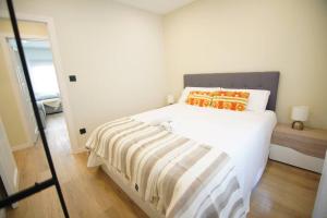 a white bedroom with a bed with a striped blanket at Apartamentos 2K - Apartamento en muelle Olabeaga in Bilbao