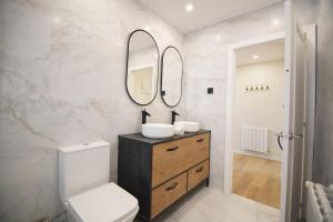 ein Badezimmer mit einem WC und zwei Spiegeln an der Wand in der Unterkunft Apartamentos 2K - Apartamento en muelle Olabeaga in Bilbao