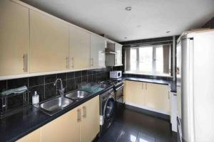 a kitchen with a sink and a washing machine at Entire 3 Bedroom House Near City Centre + FREE Parking in Manchester