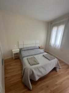 a white bedroom with a bed with two towels on it at Apartamento Nuevo Duplex in Santa Cruz de la Zarza