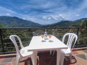 einen weißen Tisch mit zwei Weingläsern auf dem Balkon in der Unterkunft Linda finca, ideal para descansar, vista increíble in Barbosa