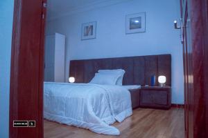 a bedroom with a large white bed with a wooden headboard at Cloud Hill in Buea