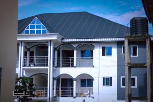 ein weißes Haus mit einem Metalldach und einem Balkon in der Unterkunft Cloud Hill in Buea