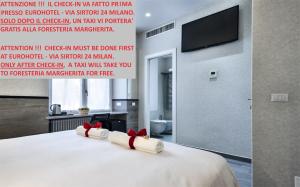 dwa białe ręczniki z czerwonymi łukami na łóżku w obiekcie Guesthouse Foresteria Margherita Milano w Mediolanie
