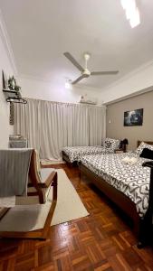 een slaapkamer met 2 bedden, een bank en een plafondventilator bij The Hill Regency in Bentong