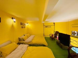 um quarto amarelo com 2 camas e uma televisão de ecrã plano em Budget 80s Style Apt @4 guests @WalkingStreet em Hanói