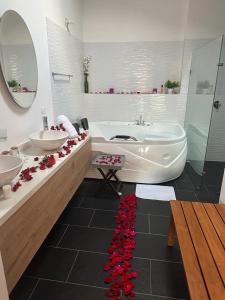 uma casa de banho com 2 lavatórios, uma banheira e flores vermelhas em Hotel Villa Teresita em Sáchica