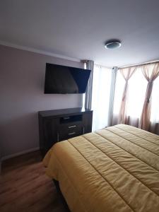 1 dormitorio con 1 cama y TV de pantalla plana en frente a playa vista panorámica Departamento 3 Habitaciones 2 Baños Iquique, en Iquique