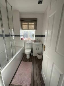 a bathroom with a toilet and a tub and a sink at Cosy home in Warrington in Great Sankey