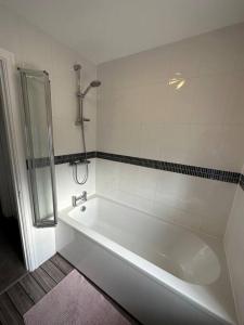a white bathroom with a tub and a shower at Cosy home in Warrington in Great Sankey