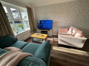 a living room with a blue couch and a tv at Cosy home in Warrington in Great Sankey