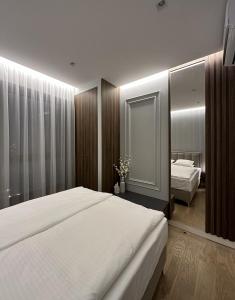 een slaapkamer met een groot wit bed en een spiegel bij DOM Boutique Apartments - Verde in Belgrado