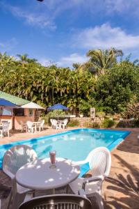 een tafel en stoelen naast een zwembad bij VELINN Feiticeira Praia Hotel in Ilhabela