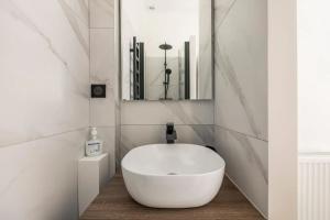 lavabo blanco en el baño con espejo en Charming apartment in heart of Le Marais - GetHosted en París