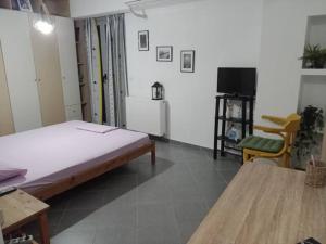 Habitación con cama, TV y mesa. en Makis rooms C, en Mesolongi