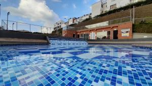 una piscina con azulejos azules en el suelo en Espectacular apartamento via Cerritos 8 personas, en Pereira