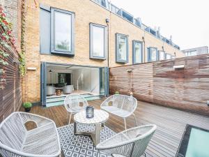 Pass the Keys London Modern EcoTownhouse Dulwich في لندن: فناء مع كراسي وطاولة على مبنى