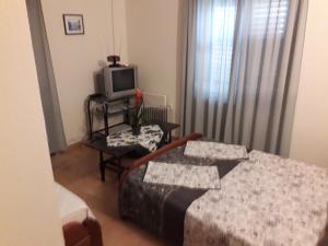 een slaapkamer met een bed en een televisie en een tafel bij Apartman Lovcen in Budva