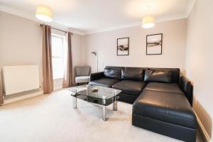 a living room with a black leather couch and a table at 4 Bedroom House with FREE WIFI AND DRIVEWAY! in Hillingdon