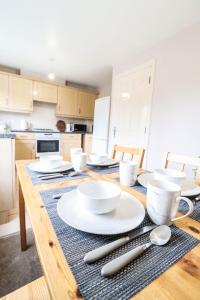 a kitchen with a table with white plates and silverware at Family-Friendly 4 Bedroom House with Private Driveway in Hillingdon