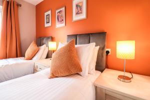 two beds in a bedroom with orange walls at Family-Friendly 4 Bedroom House with Private Driveway in Hillingdon
