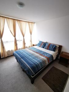 a bedroom with a bed with a blue comforter and two windows at Maravilloso Depto 3 habitaciones 1 baño - familiar Iquique in Iquique