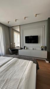 een slaapkamer met een bed en een televisie aan de muur bij DOM Boutique Apartments - Verde in Belgrado