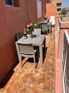 un patio con mesas, sillas y flores en el balcón en Appartement haut standing 3 chambres avec Terasse quartier Gueliz / Hivernage à Marrakech en Marrakech