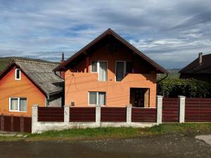 ein braunes Haus mit einem Zaun davor in der Unterkunft North Transylvania room 2 