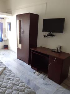 a bedroom with a desk and a television on the wall at Hotel Paradise Inn in Tiruppūr