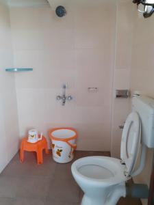 ein Badezimmer mit einem weißen WC und einem orangenen Stuhl in der Unterkunft Hotel Paradise Inn in Tiruppūr