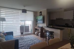 a living room with a couch and a kitchen at Cómodo departamento full equipado con piscina in Villarrica