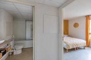 La salle de bains est pourvue d'un lit, de toilettes et d'un lavabo. dans l'établissement Les Cocons de Lourdes, à Lourdes