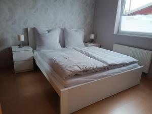 a bed with white sheets and pillows in a bedroom at Ferienwohnung Limper in Hilchenbach