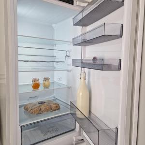 an empty refrigerator with a bottle and a glass shelf at Stylish bungalow with complimentary breakfast on the first morning in Lancing