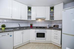 una cocina blanca con armarios y electrodomésticos blancos en MAEVA HomeStay by Turismar, en Cambrils