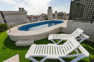 two white lounge chairs and a pool on a rooftop at MAEVA HomeStay by Turismar in Cambrils